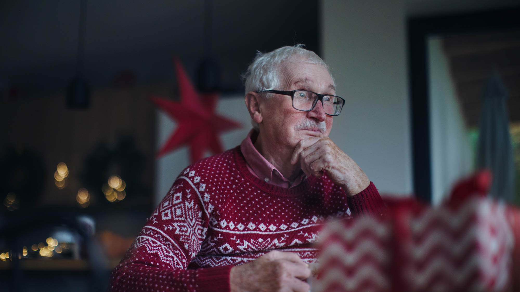 Old man in Christmas jumper looking sad