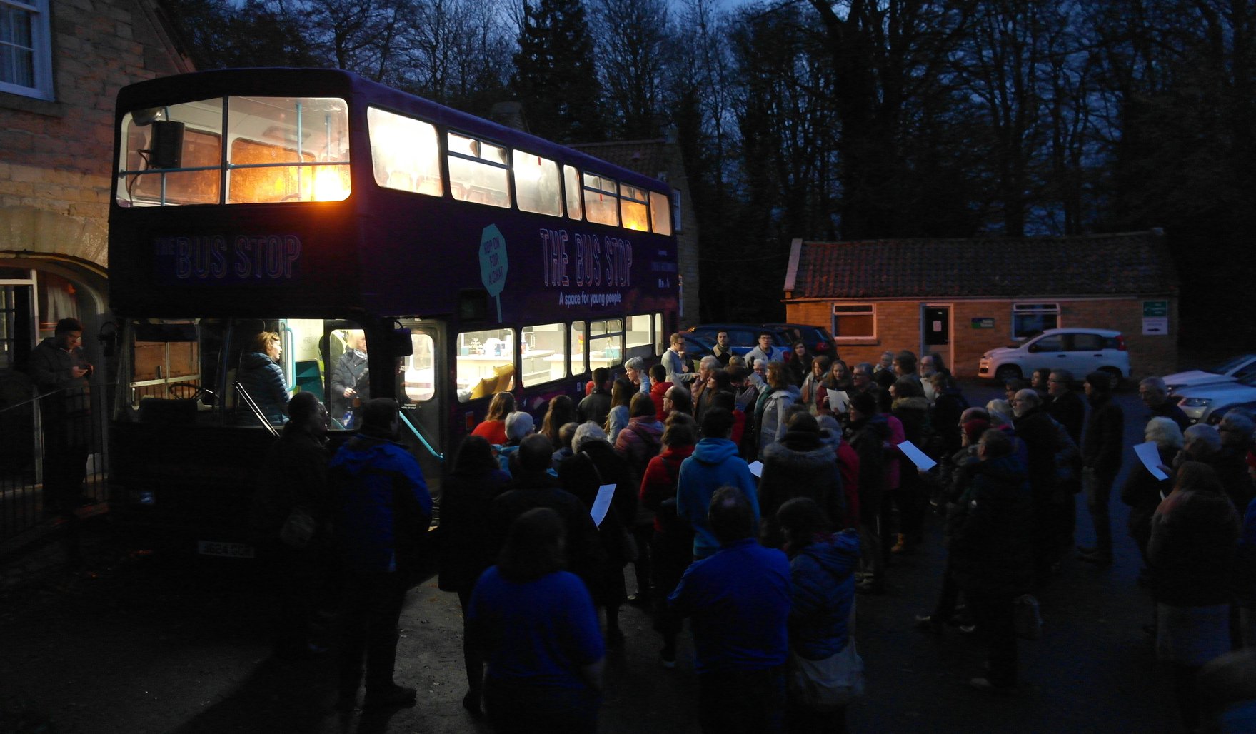 Large group of people surrounding double-decker bus